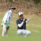 nakajima assisting by hid caddies showing the slope of green