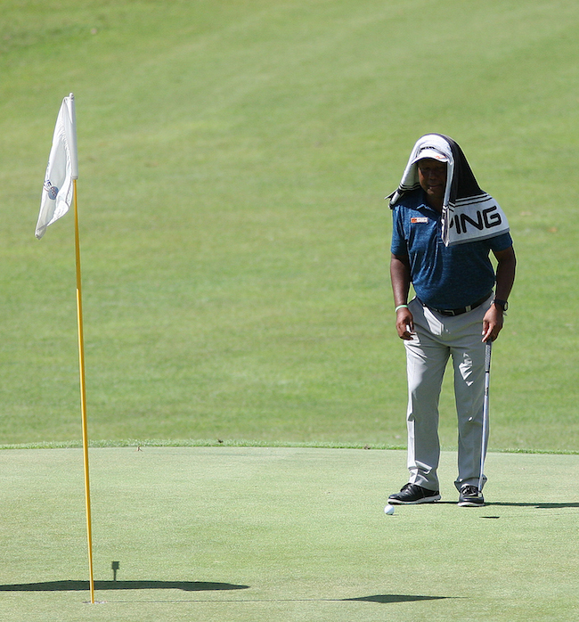 Tony Lascuña uses his towel to fight off the heat as he reads the line of his putt on No. 18